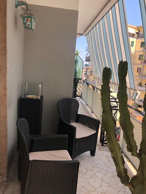 A balcony with wicker furniture, a cactus, and a view of buildings. - Spacious 3-bedroom apartment with AC, WiFi in beautiful Napoli (Napoli)