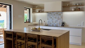 Une cuisine moderne dotée d’un îlot central, de chaises en bois, d’un évier encastré et d’un pare-feu en carreaux.