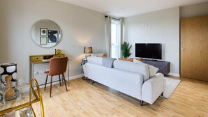 A modern living room with a sofa, TV, desk, and chair. - The Enfield Sanctuary - Modern 1bdr Flat With Balcony (Enfield)