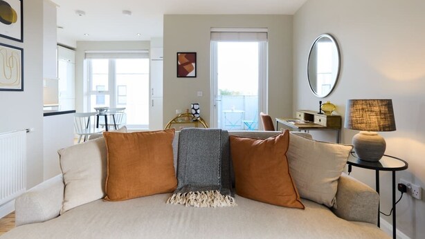 A modern bedroom with a large bed, a small table with a lamp, and a view of the balcony. - The Enfield Sanctuary - Modern 1bdr Flat With Balcony (Enfield)