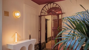 Un espace intérieur bien éclairé, avec une console blanche, une lampe et une chaise sur laquelle se trouve un saladier rempli de fruits.