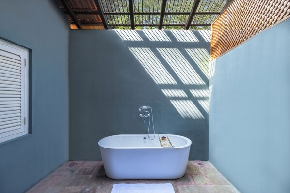 A modern bathroom with a freestanding bathtub, a showerhead, and a towel on the floor. - Rambha Palace (Chatrapur)