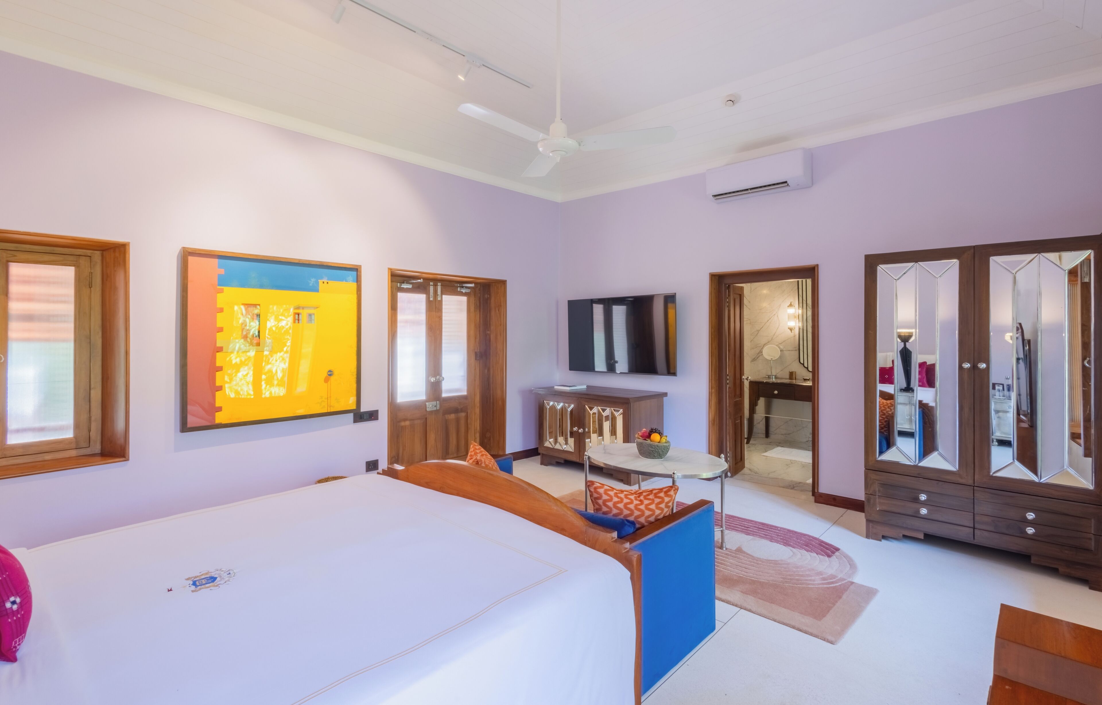 A bedroom with a bed, a TV, a wardrobe, and a mirror.