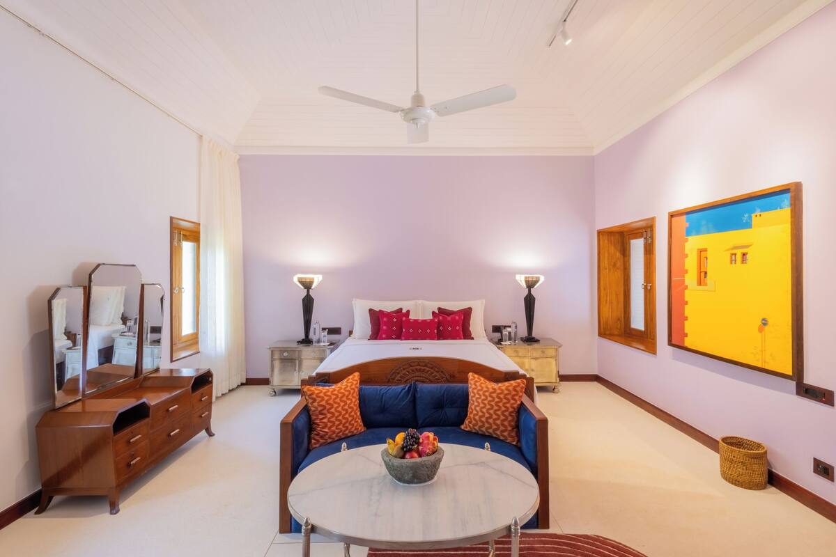 Une chambre à coucher comprenant un lit, des tables de chevet, une commode, un canapé et un ventilateur de plafond.