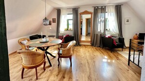 A spacious living area with a wooden floor, a round dining table with chairs, a sofa, and a TV stand. - Fewo Hiddensee Mecklenburg Pool Alte Schule Barlin (Dargun)