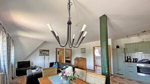 A cozy living room with a wooden dining table, a sofa, and a television. - Vacation apartment Rügen Alte Schule Barlin Mecklenburg Pool (Dargun)