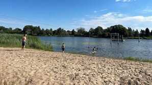 A sandy beach with a lake, a dock, and trees in the background. - Vacation apartment Rügen Alte Schule Barlin Mecklenburg Pool (Dargun)