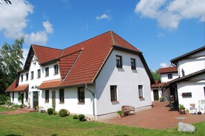 Stunning two-story residence with a red-tiled roof and white walls, featuring a front entrance with a door and windows on both floors.
