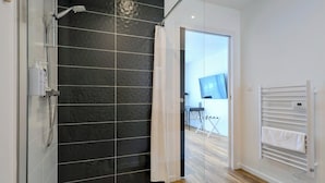 Une salle de bain moderne avec une douche à parois de verre, un porte-serviettes blanc et un plancher en bois.