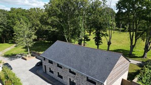 Un bâtiment en pierre doté d’un toit en pente, d’une allée pavée et d’un petit espace extérieur aménagé pour s’asseoir.