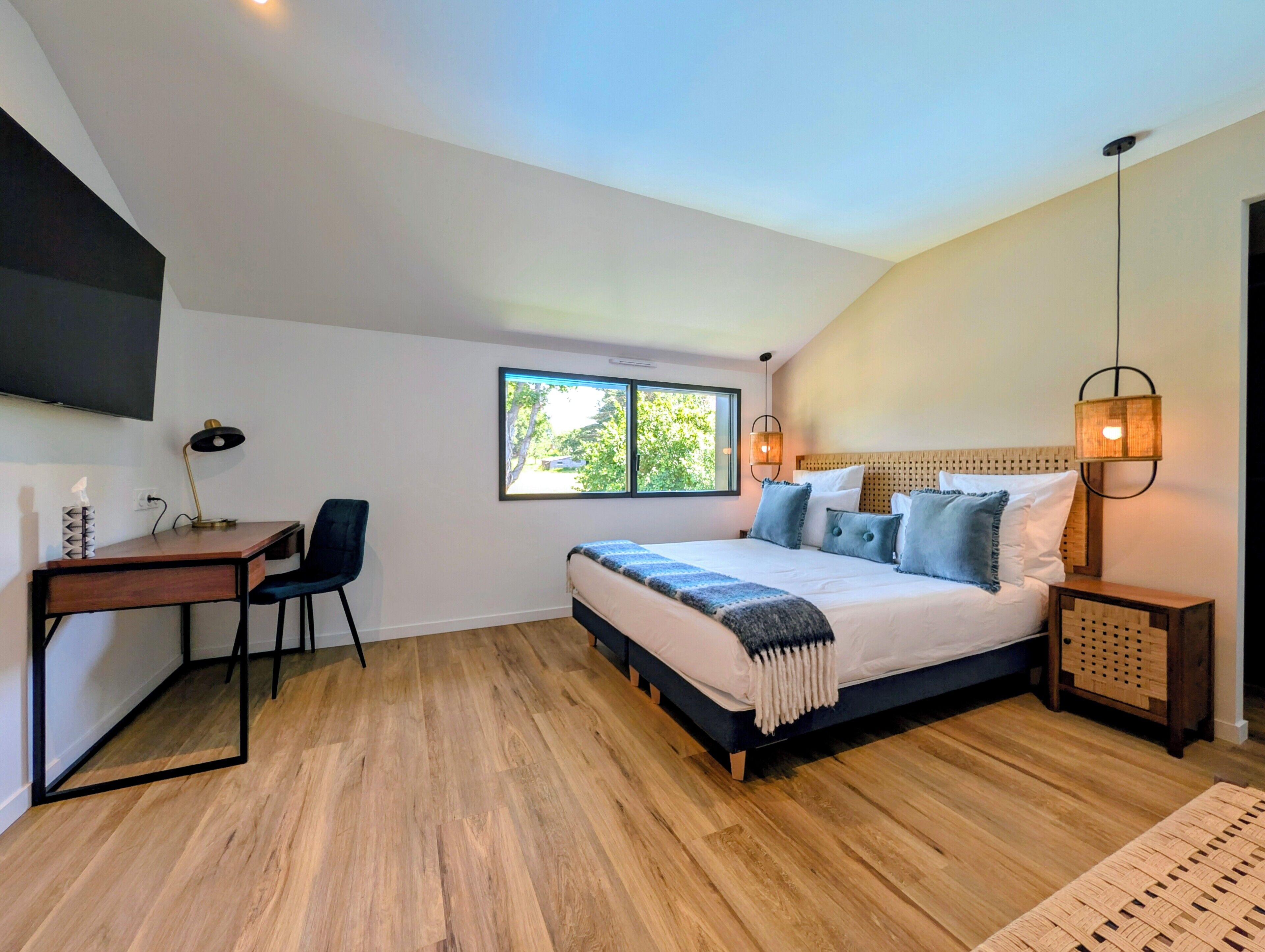A bedroom with a bed, desk, chair, and a TV mounted on the wall.