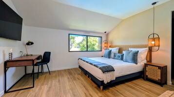 A bedroom with a bed, desk, chair, and a TV mounted on the wall.