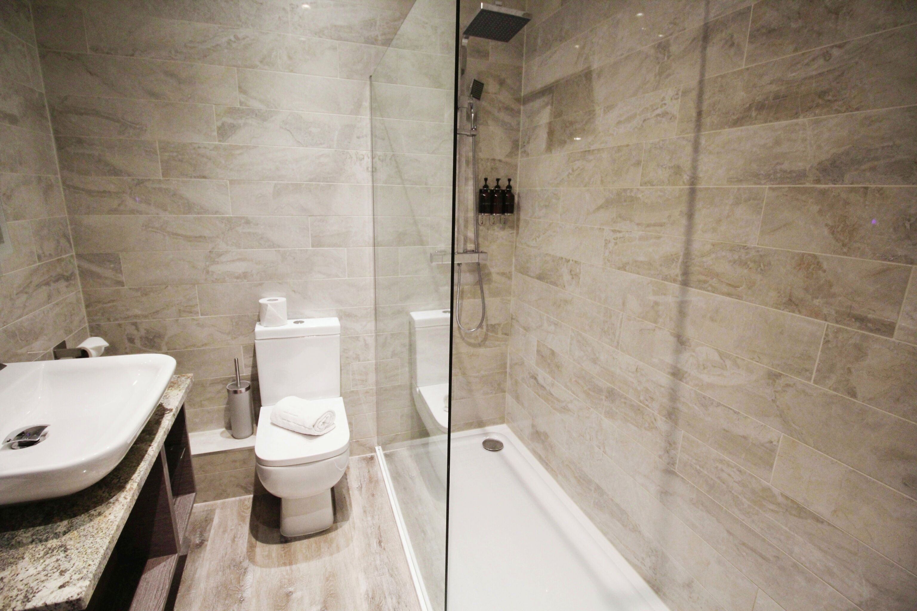 A modern bathroom with a glass-enclosed shower, a white sink, and a toilet.