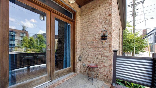 Une terrasse en bois avec une porte vitrée donnant sur un espace patio.