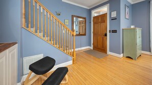 Un escalier avec des balustrades en bois, un banc, une armoire verte et une porte donnant sur une autre pièce.