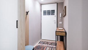 A hallway with a door, a small desk, and a patterned rug. - Easylife - Elegant flat at Castello Sforzesco (Milan)