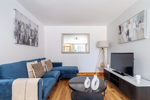 A modern living room with a blue sofa, a coffee table, a TV, and artwork on the walls.