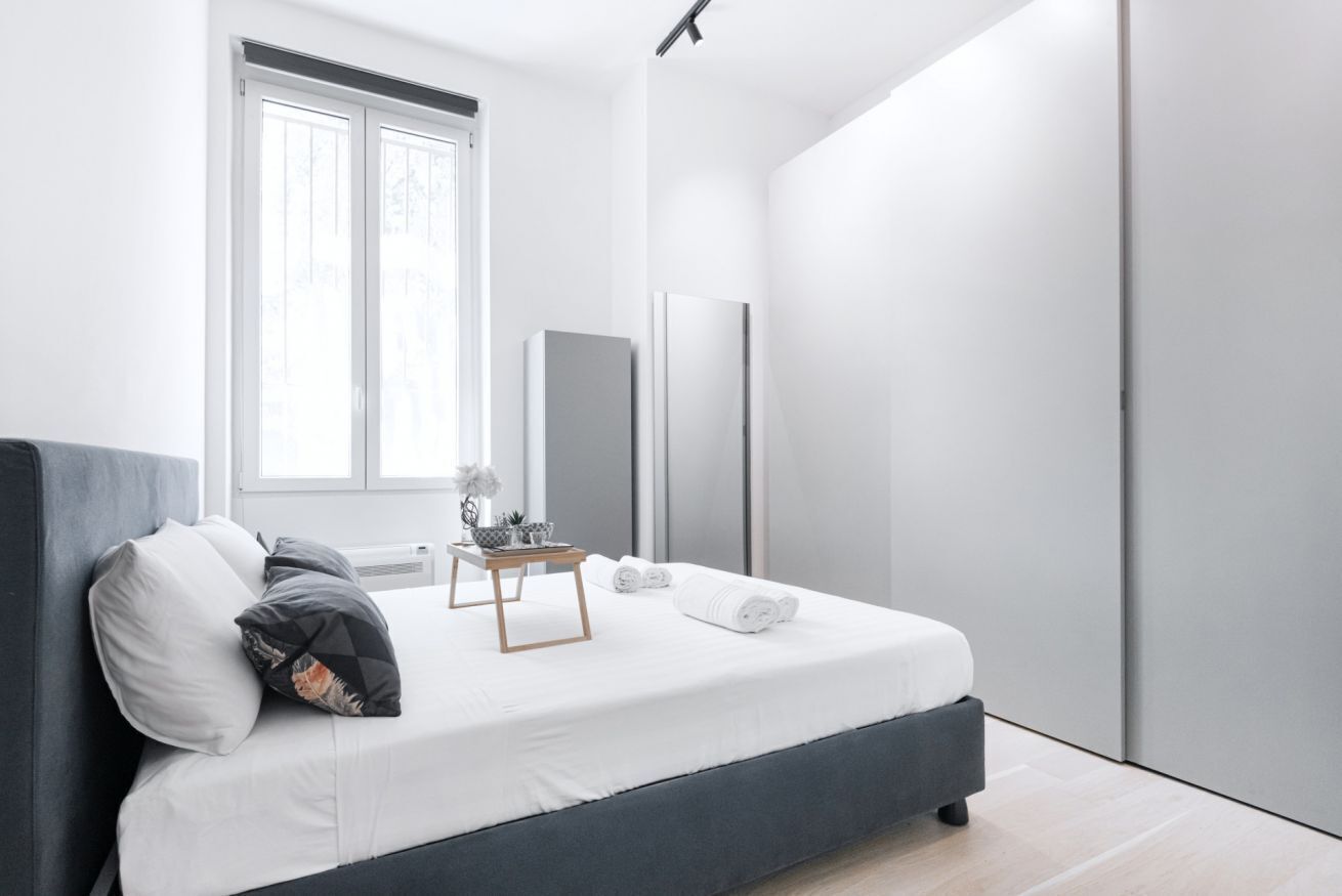 Une chambre à coucher moderne avec un lit, une table de chevet et une grande fenêtre.