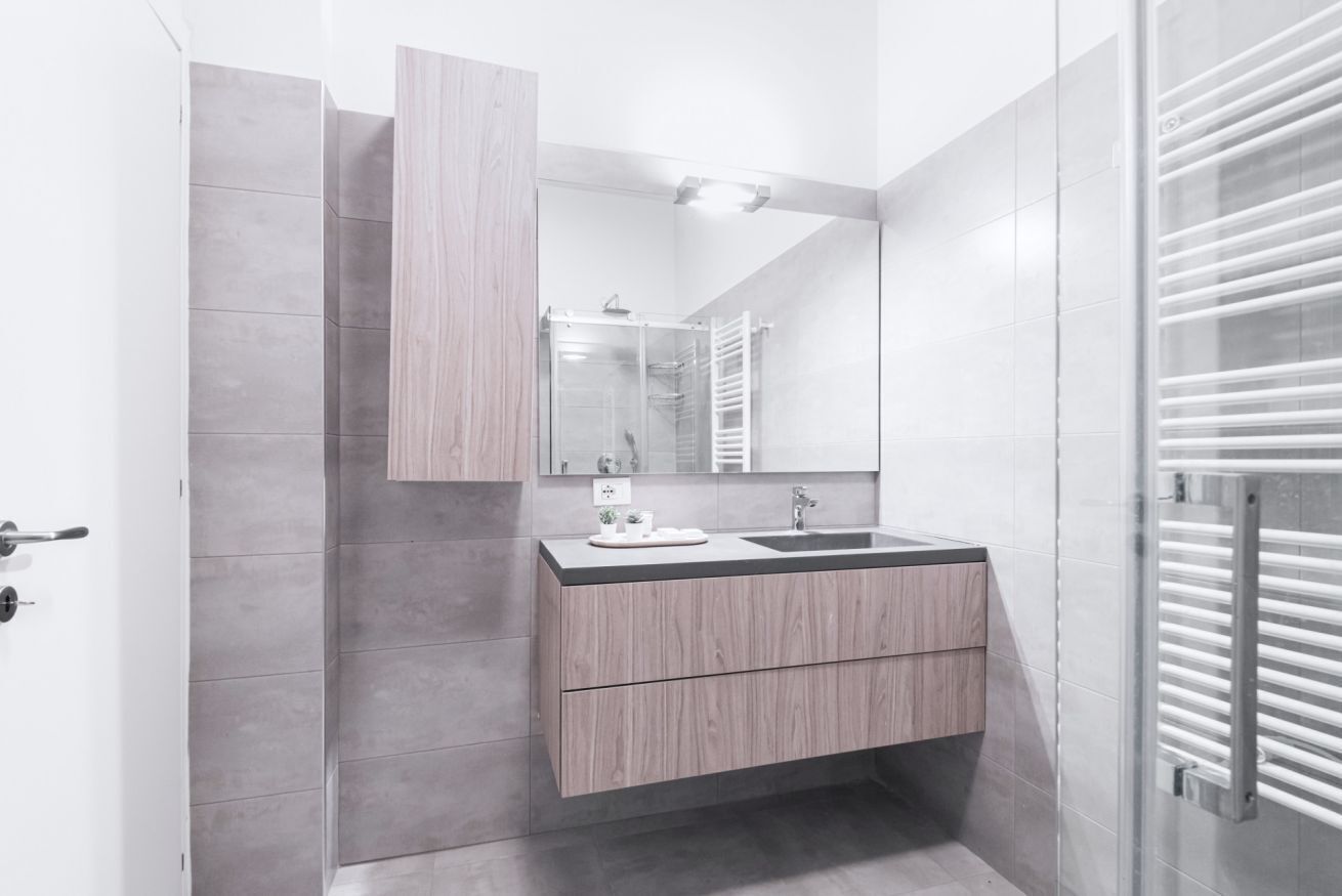 A modern bathroom with a wooden vanity, a large mirror, and a towel rack.
