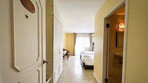A hotel corridor with a bed, a bathroom, and a dining area. - Rajpracha Pakchong (Pak Chong)
