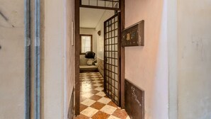 A hallway with a checkered floor, a metal gate, and a wall-mounted sign. - AureliaHome@Pescheria (Treviso)