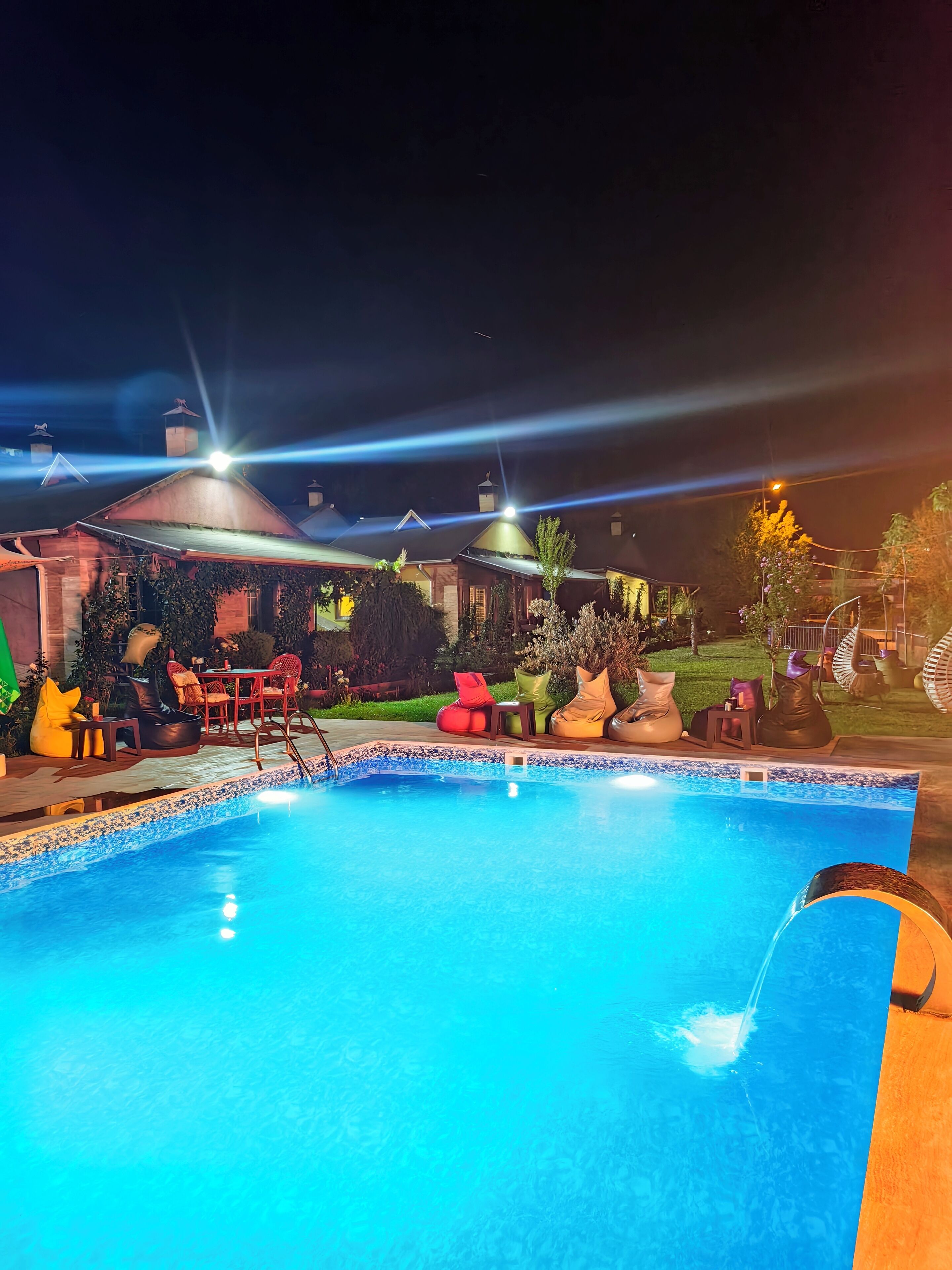A swimming pool with lounge chairs and a covered seating area.