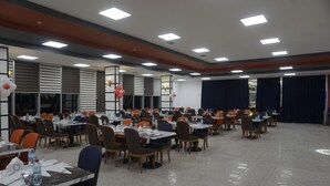 A large, well-lit conference room with multiple tables and chairs, equipped with water bottles and papers, suggesting a meeting or event setup. - Celik Hanim Termal Otel & Spa (Ulukisla)