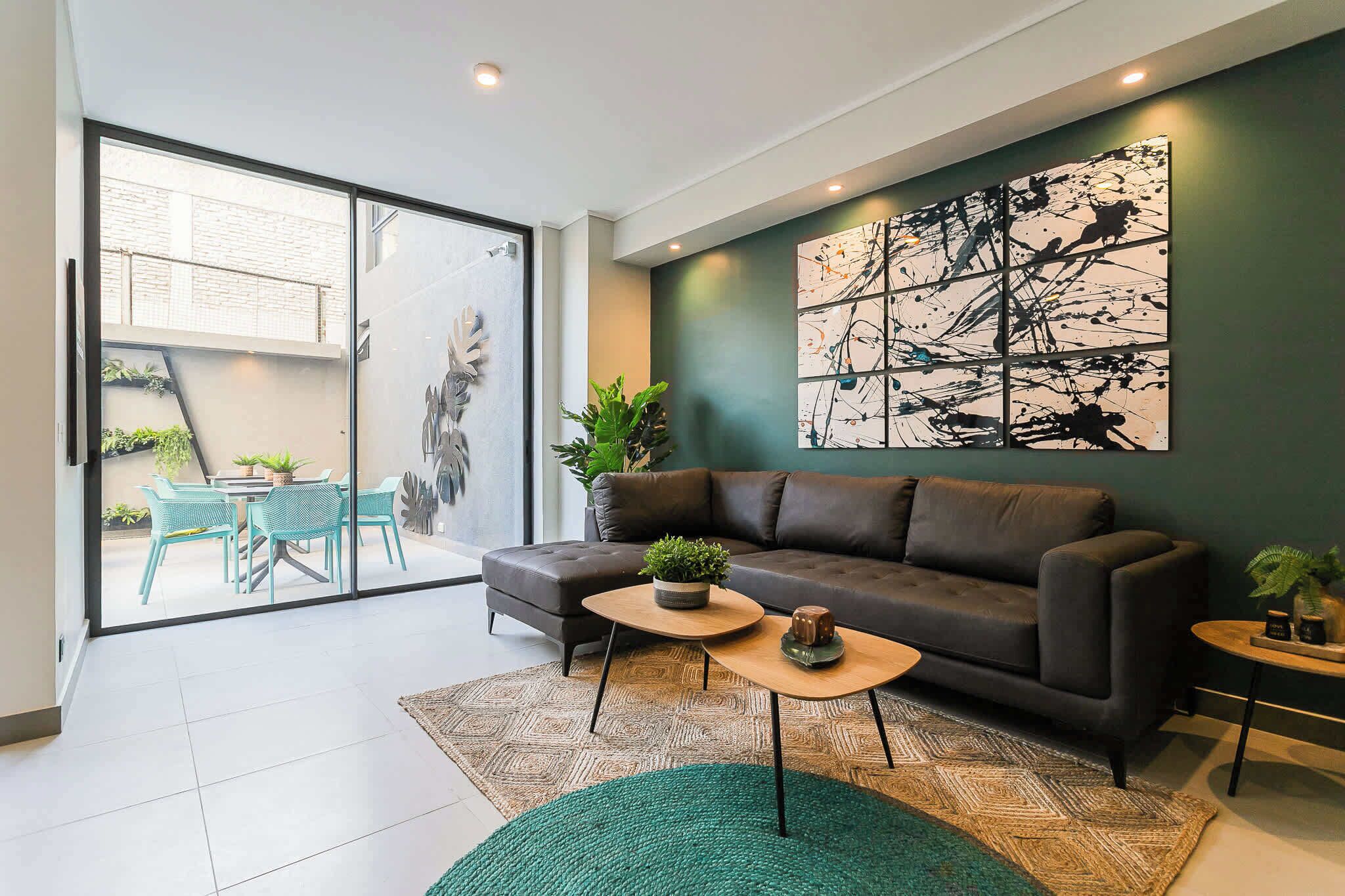 A modern living room with a sofa, coffee table, and a large abstract painting on the wall.