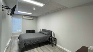 A bedroom with a bed, bedside table, and a TV mounted on the wall. - Private Apartment in Southbury 102 (Southbury)