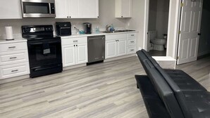 A modern kitchen with white cabinets, a stainless steel microwave, a black oven, and a dishwasher. - Private Apartment in Southbury 102 (Southbury)
