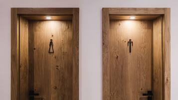 Two wooden doors with a light fixture above each, one with a triangular symbol and the other with a human figure symbol.