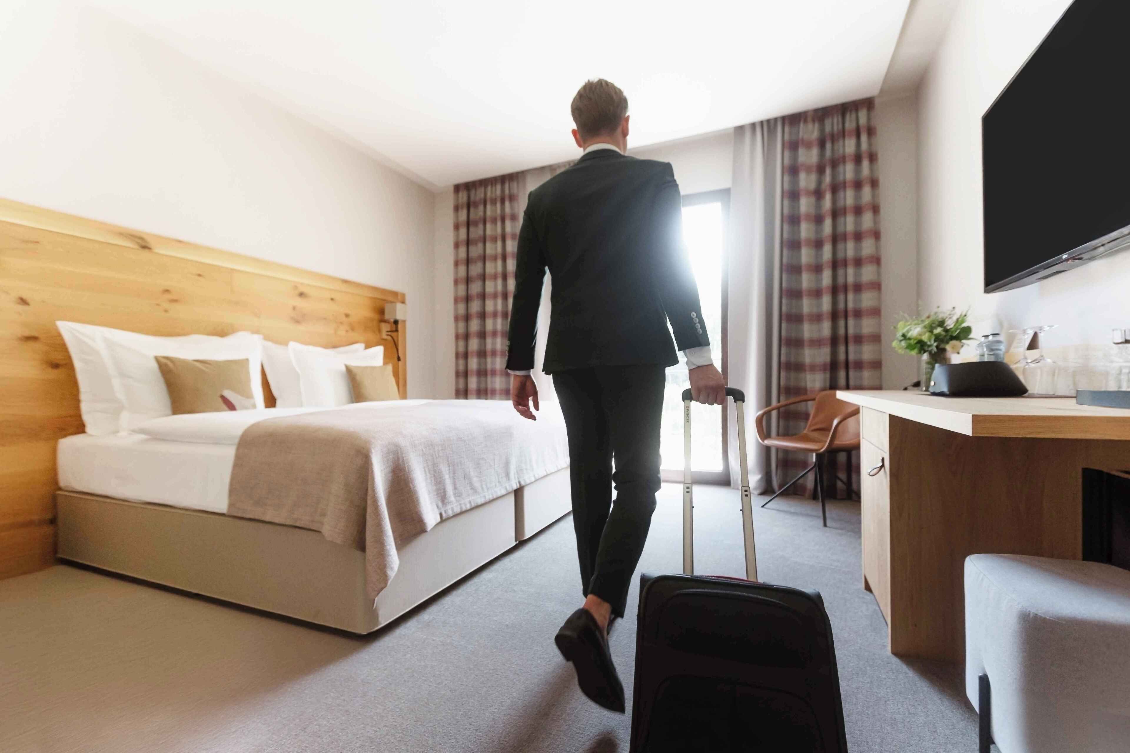 A hotel room with a bed, a desk, a chair, and a TV.