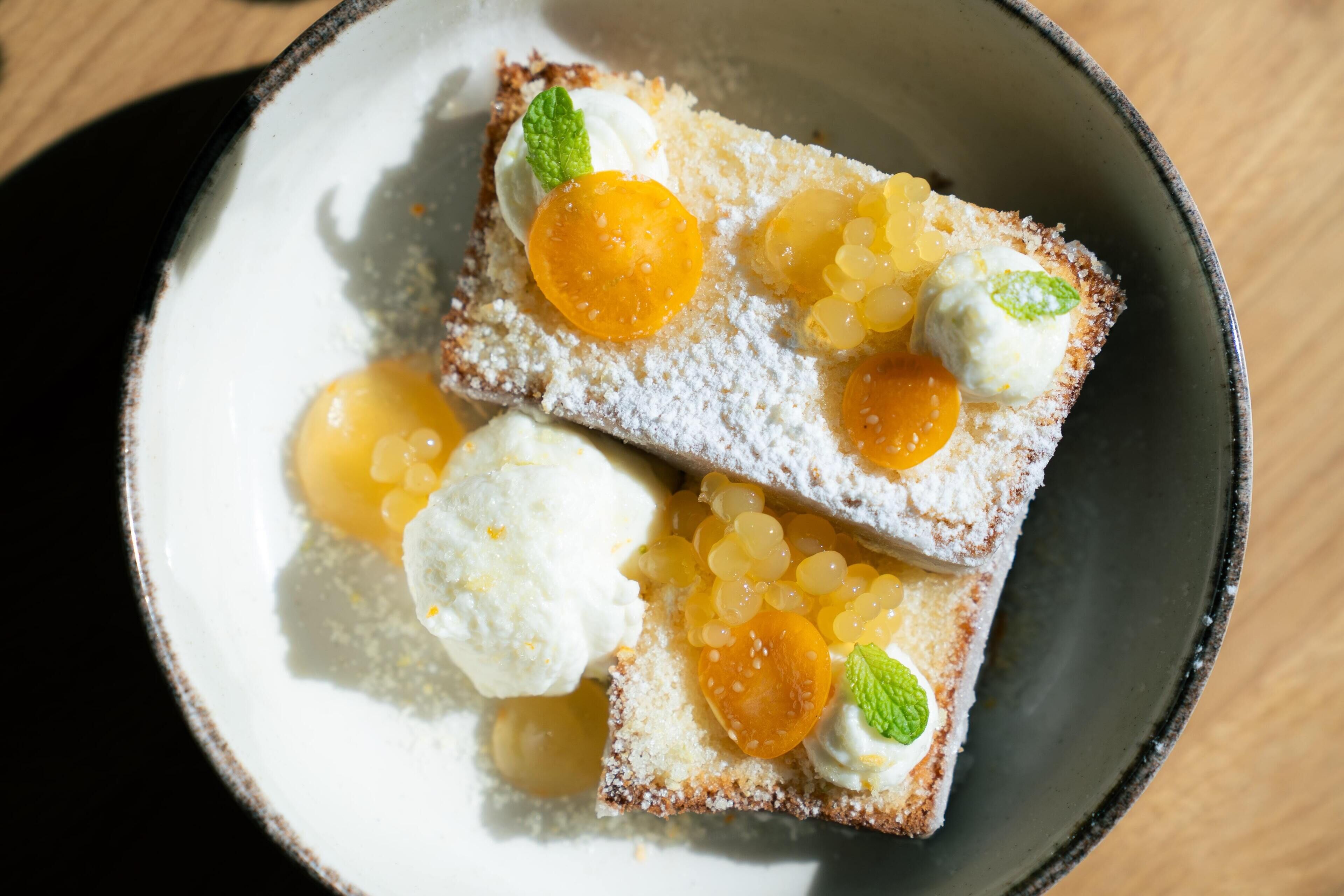 Uma sobremesa com fruta e creme num prato.