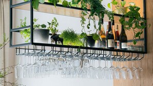 Uma área de bar com adega, copos e plantas em vasos.