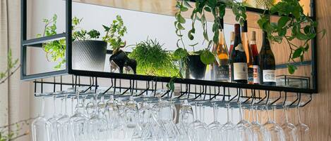 A bar area with a wine rack, glasses, and potted plants.