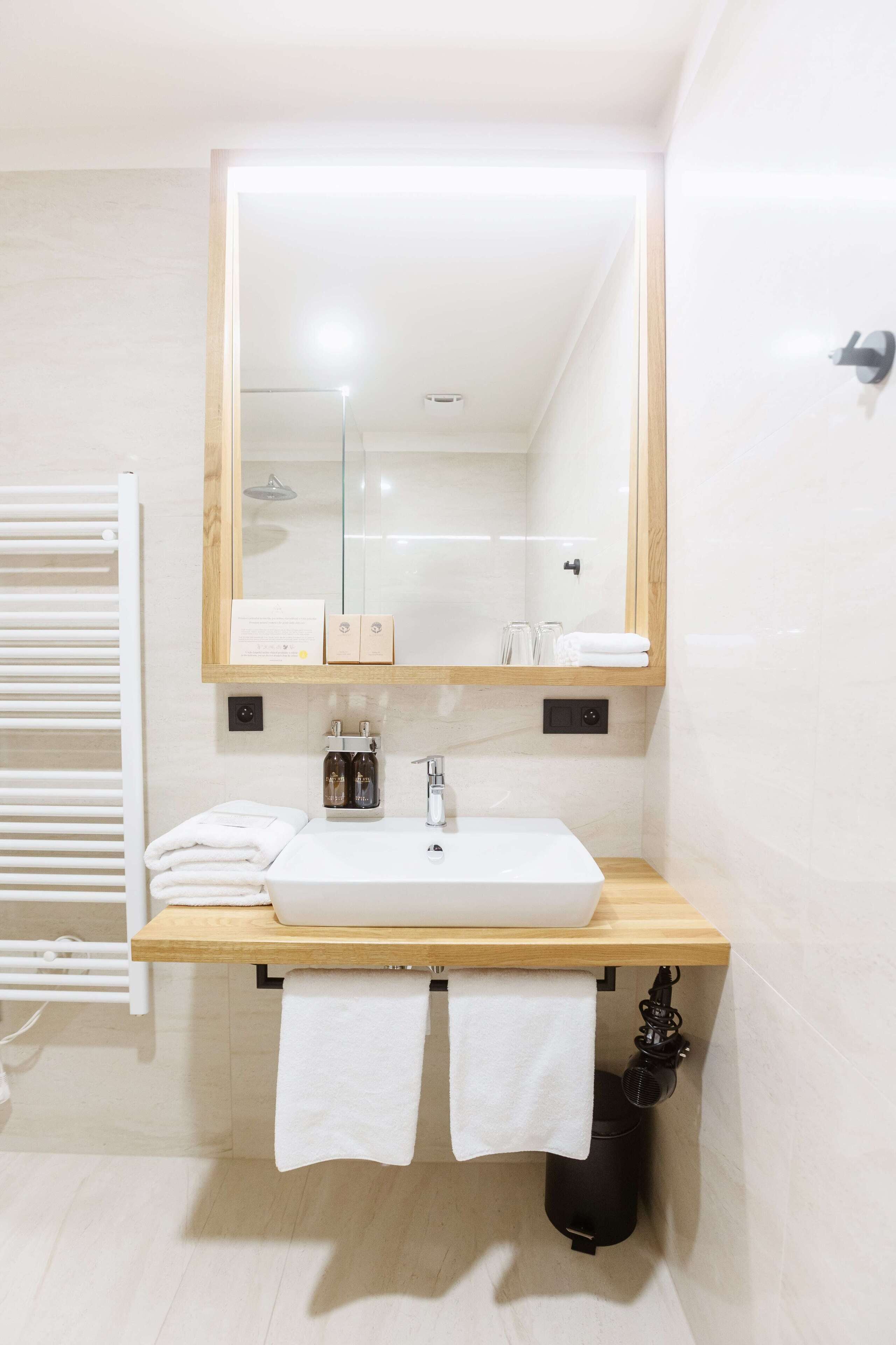 Ein modernes Badezimmer mit einem weißen Waschbecken, einer Holztischplatte und einem großen Spiegel.