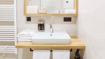 Ein modernes Badezimmer mit einem weißen Waschbecken, einer Holztischplatte und einem großen Spiegel.
