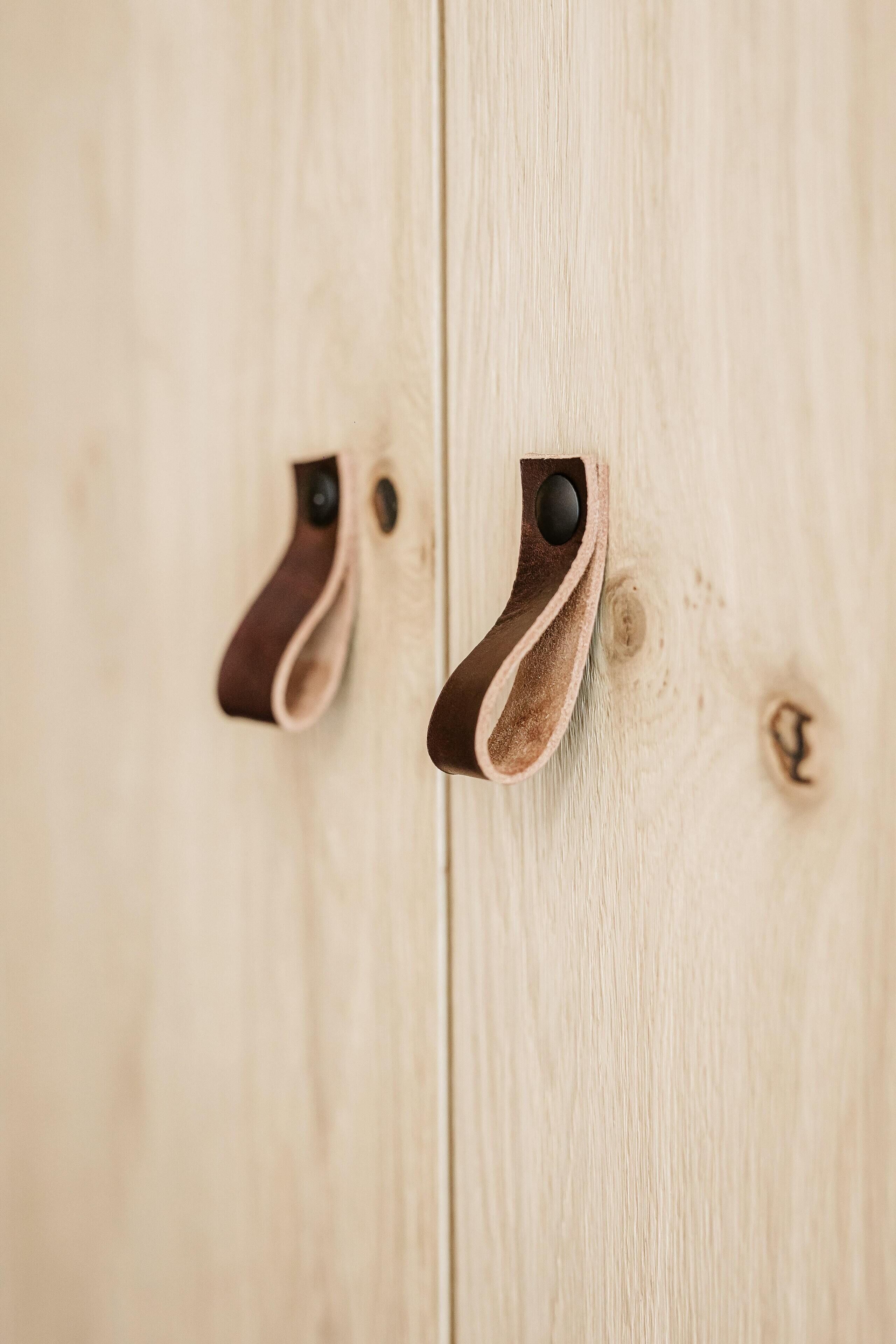 Una puerta de madera con dos manijas de cuero marrón.