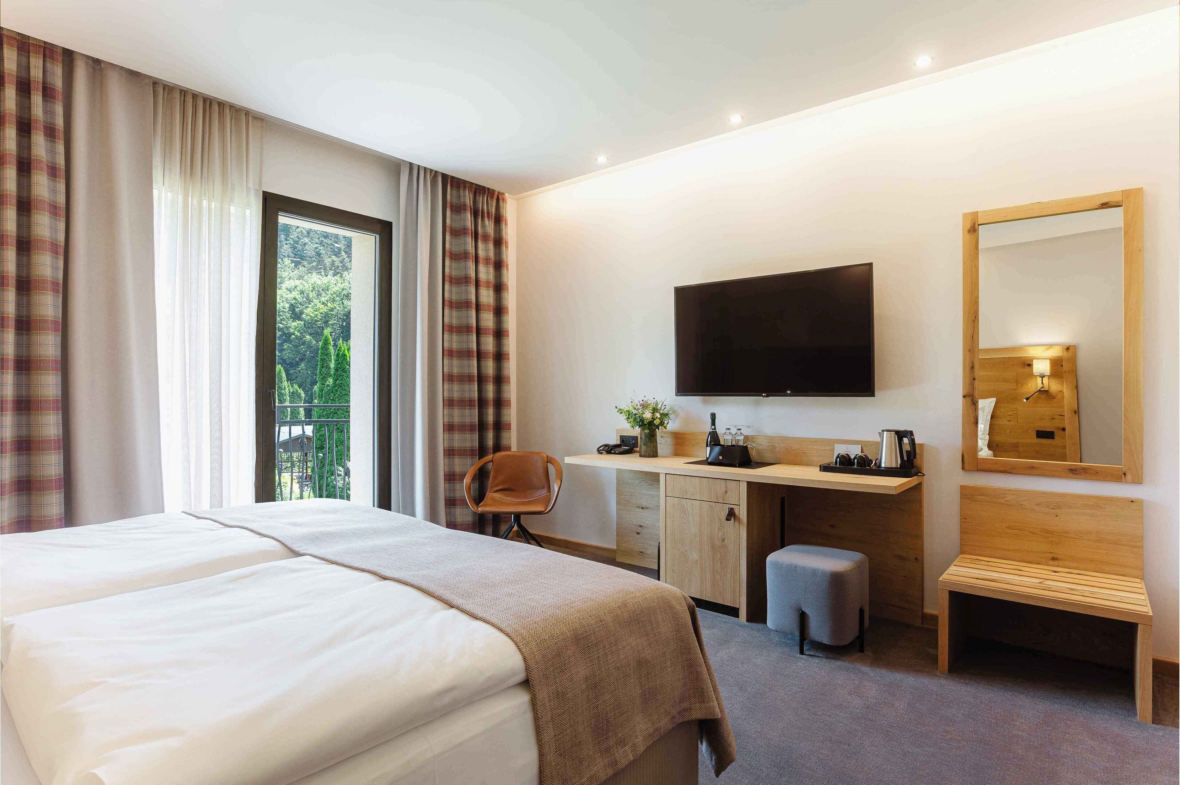 Habitación de hotel con una cama grande, un escritorio, una silla, un televisor y un espejo.
