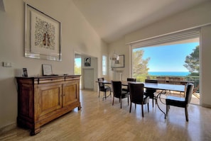 A dining area with a wooden cabinet, framed artwork, and a table with chairs.
