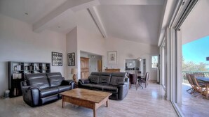 A spacious living room with a sofa, coffee table, and dining area. - FRGK Villa Le Petit Bois Panoramic View, Lush Ga (vallauris)