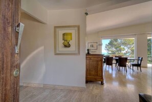 Une pièce spacieuse avec un plancher en bois, un coin repas comprenant des chaises et une table, et une œuvre d’art encadrée accrochée au mur.