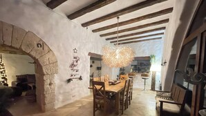 A rustic dining area with a wooden table and chairs, a hanging light fixture, and a stone archway. - 1800 Year Watermill 5-bed Farm House in Penaguila (Penaguila)