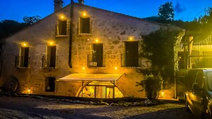 A stone building with multiple windows, a covered outdoor seating area, and a parked car. - 1800 Year Watermill 5-bed Farm House in Penaguila (Penaguila)