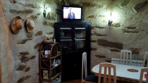 A rustic dining area with a tiled floor, wooden chairs, a table, and a television on a shelf. - Beautiful 8 -bed Cottage in Ceadeaspain, (Fonfria)