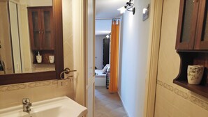 A bathroom with a sink, mirror, and wooden cabinets. - Marilena Cottage Between sea and Nature (Sperlonga)