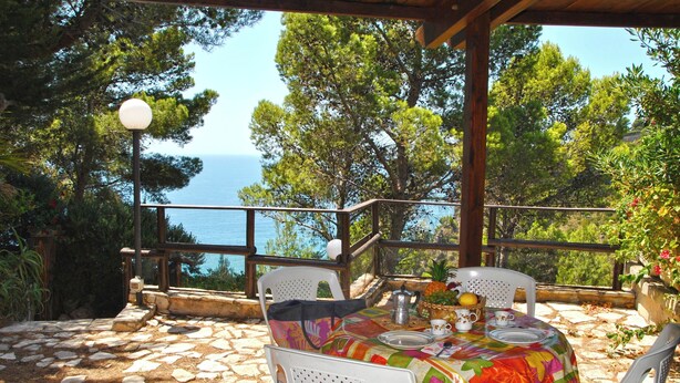 An outdoor dining area with a table set for two, overlooking a scenic view of the sea. - Marilena Cottage Between sea and Nature (Sperlonga)