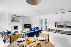 Ein modernes Wohnzimmer mit Essbereich, Küche und Kamin.