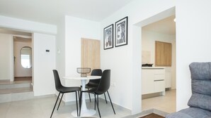 A modern living room with a glass coffee table, black chairs, a grey sofa, and a kitchen in the background. - Cozy 1 Bd Basement Apt in Pagrati (Athens)