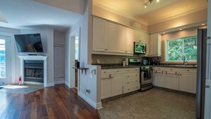 A modern kitchen with white cabinets, a built-in oven, and a large window. - Spa & Nature | Le Havre du Confort (Saint-Colomban)